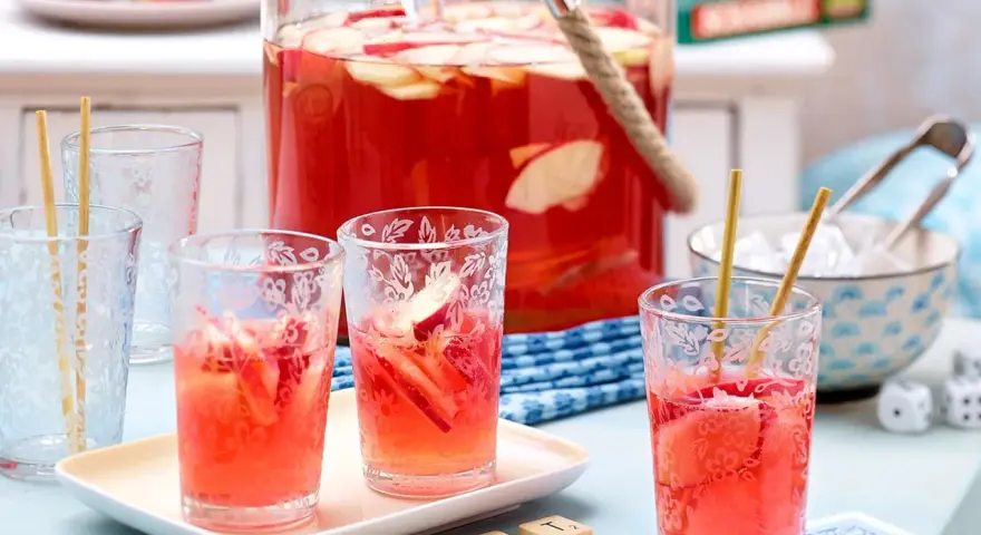 Erfrischende alkoholfreie Bowle mit Apfelstücken in Gläsern, bereit für ein sommerliches Treffen.