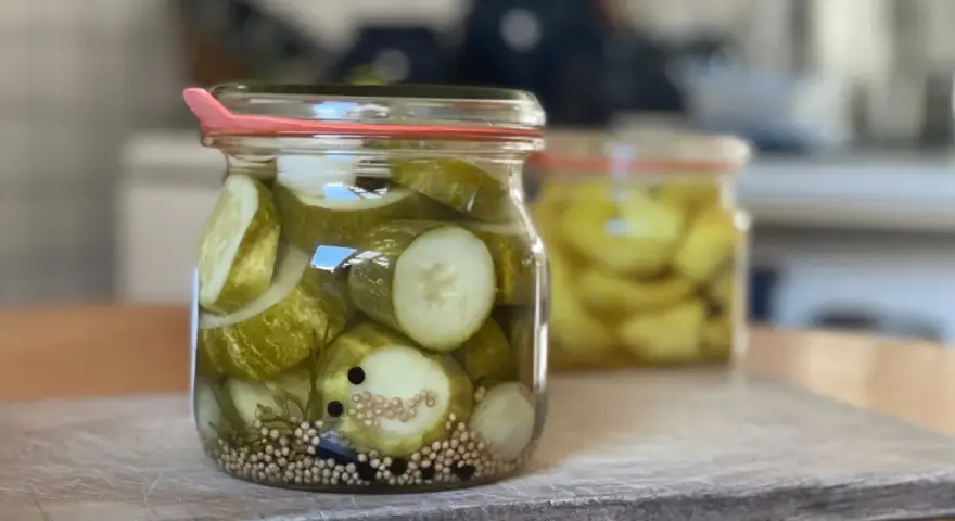 Einmachgläser mit Gurkenscheiben, Zwiebeln und Gewürzen. So werden Gurken eingelegt nach Omas Rezept.