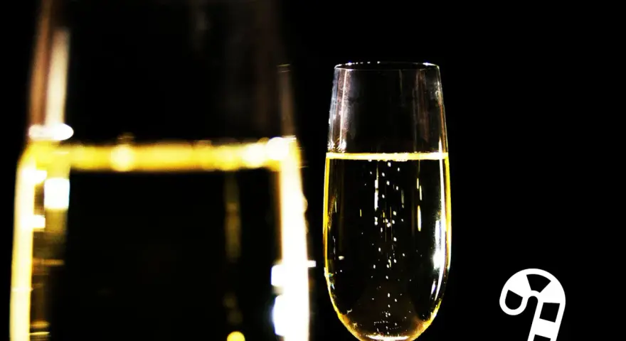Ein Glas Champagner mit Bläschen, daneben ein Zuckerstangen-Symbol. Die richtige dosage Champagner für den festlichen Anlass.