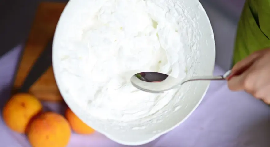 Eine Schüssel mit frisch geschlagener Sahne, bereit für ein Dessert. Ein Löffel ruht in der luftigen Masse.