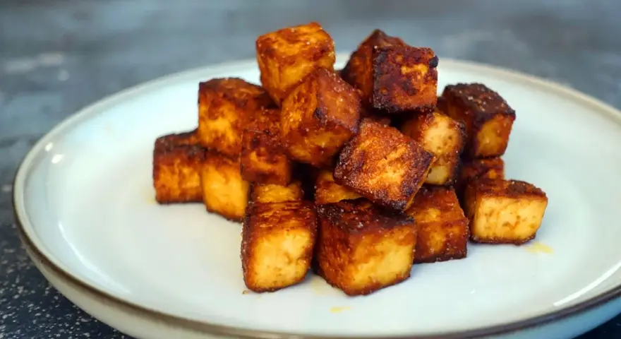 Goldbraun gebratene Tofuwürfel, perfekt zum tofu zubereiten. Knusprig und lecker auf einem Teller angerichtet.