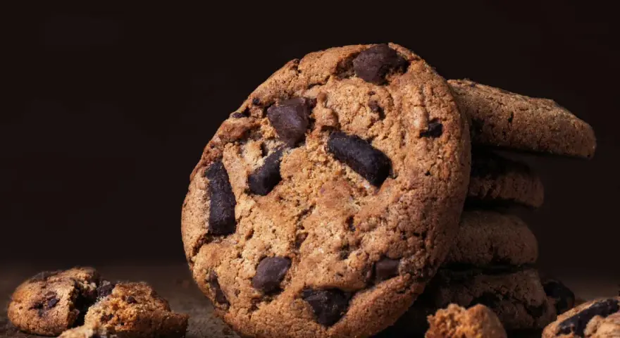 Ein Stapel saftiger american cookies mit Schokoladenstückchen auf einem Holztisch.