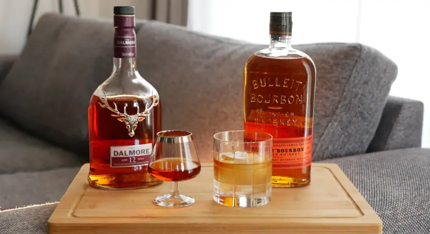 Zwei Flaschen und Gläser mit Whiskey zeigen die whiskey sorten unterschiede: ein Dalmore Scotch und ein Bulleit Bourbon.