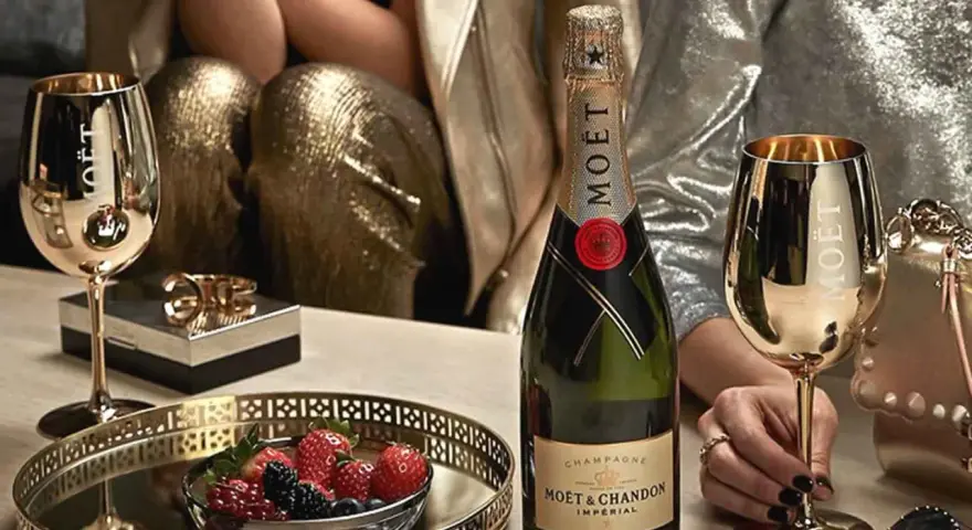 Elegante Szene mit Moët & Chandon Champagnerflasche, goldenen Gläsern und Beeren. Die Herkunft des Luxus wird durch die Marke und die festliche Atmosphäre betont.