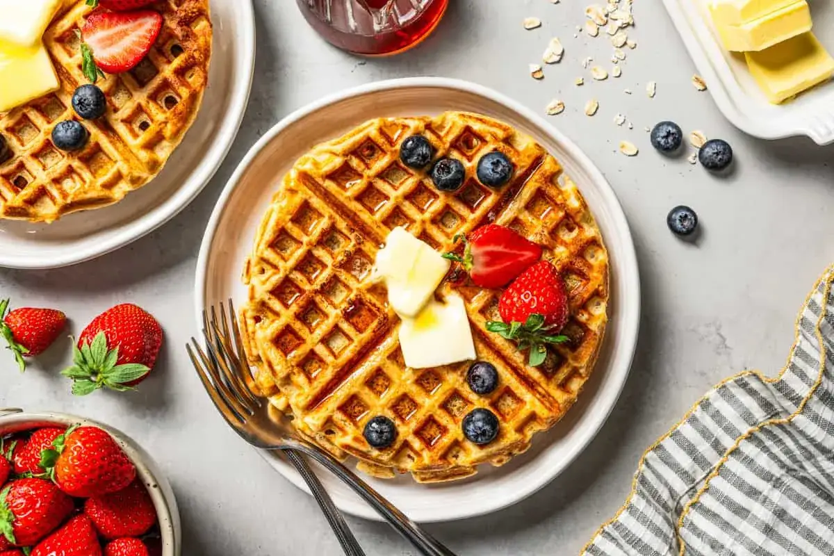 Goldbraune protein waffeln mit Butter, Erdbeeren und Blaubeeren, serviert mit Sirup.