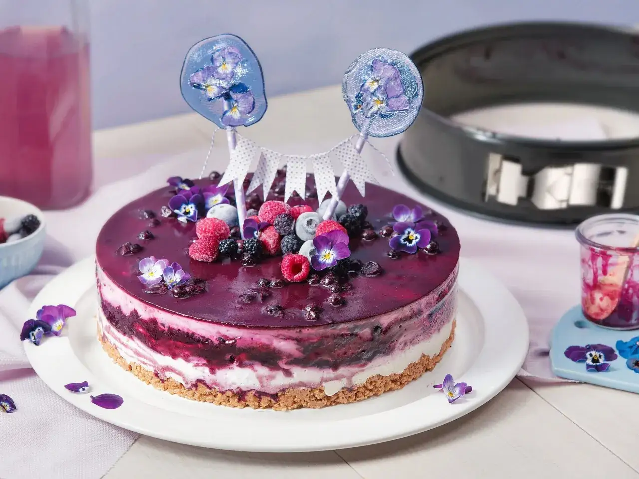 Eine einfache Torte mit Beeren und Veilchen, verziert mit zwei Lollis.