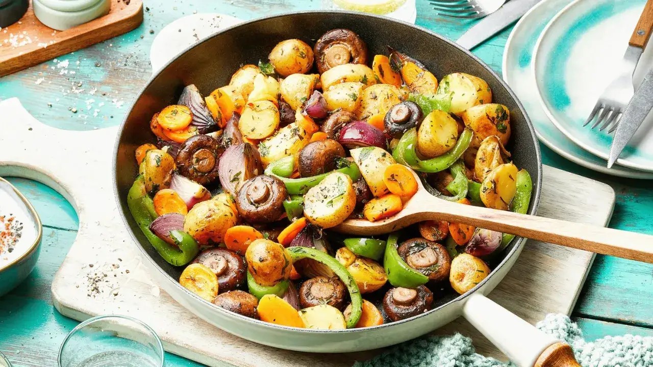 Bunte Bratkartoffeln, Pilze, Karotten und Paprika in einer Pfanne – ein Beweis für schnelle Gerichte, die köstlich aussehen und schmecken.