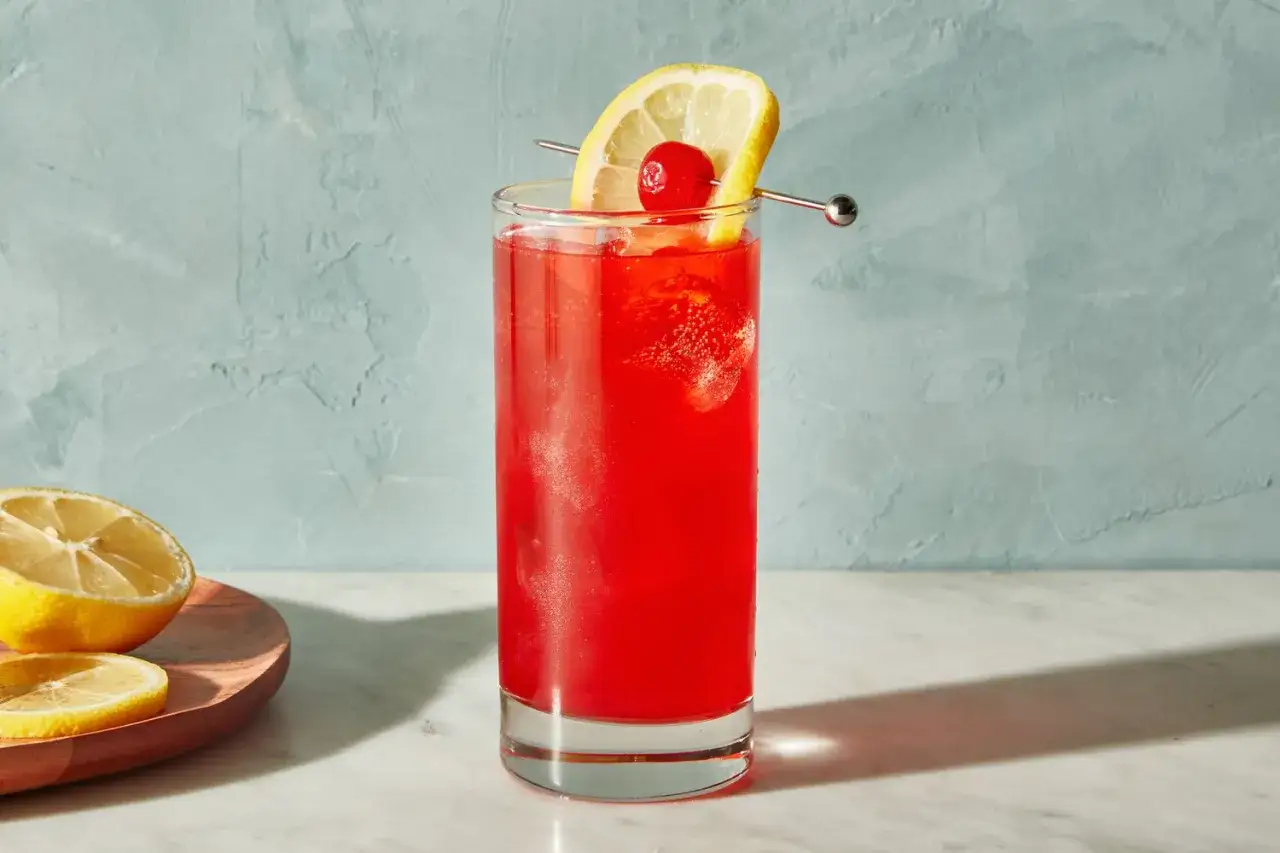 Ein erfrischender Sling Cocktail mit Zitrone und Kirsche, bereit zum Genießen.