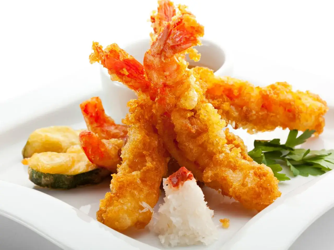Knusprige tempura garnelen mit Zucchini und einem Berg aus geriebenem Rettich, garniert mit Petersilie.