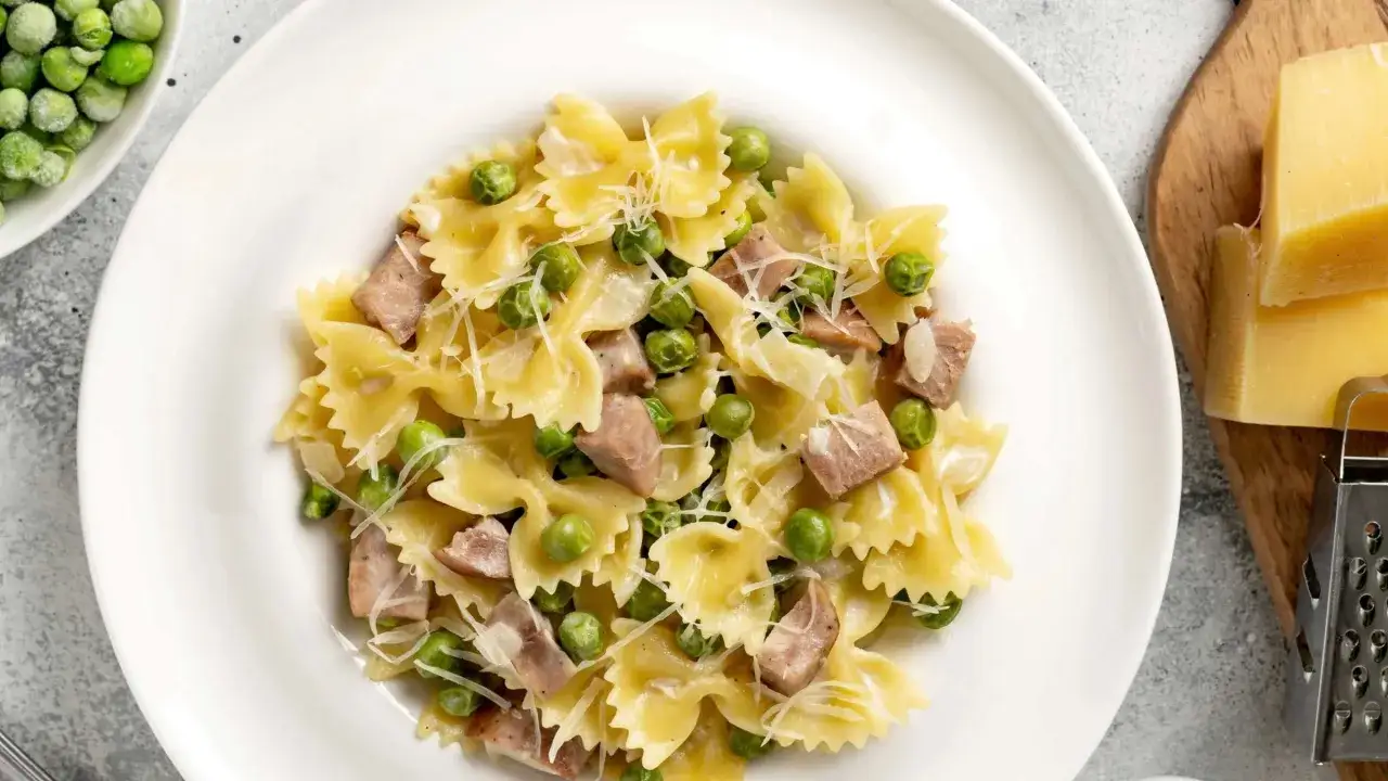 Farfalle-Pasta mit Erbsen und Speck, bestreut mit Parmesan. Ein einfaches und leckeres Gericht, perfekt für schnelle Pasta Rezepte.
