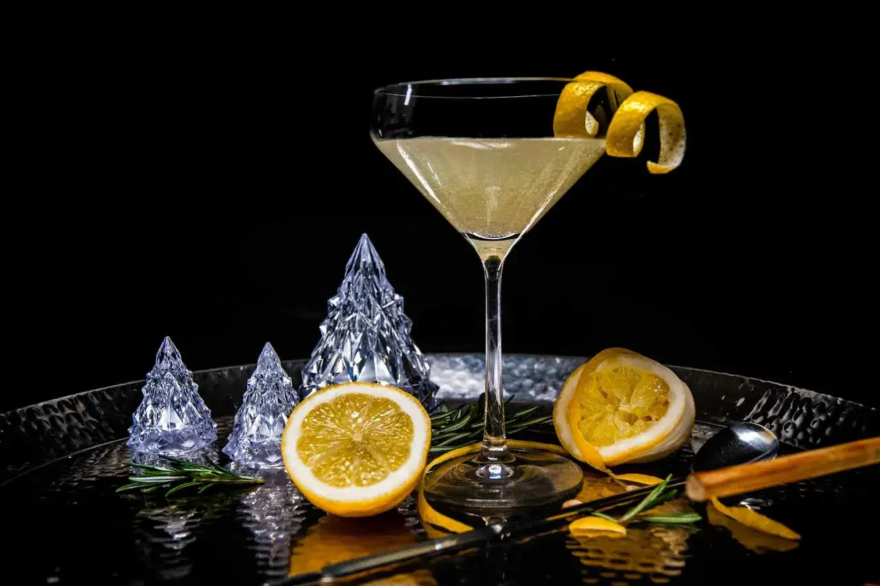 Ein eleganter French 75 Cocktail mit Zitronenzeste, dekoriert mit Kristall-Tannenbäumen und Rosmarin.