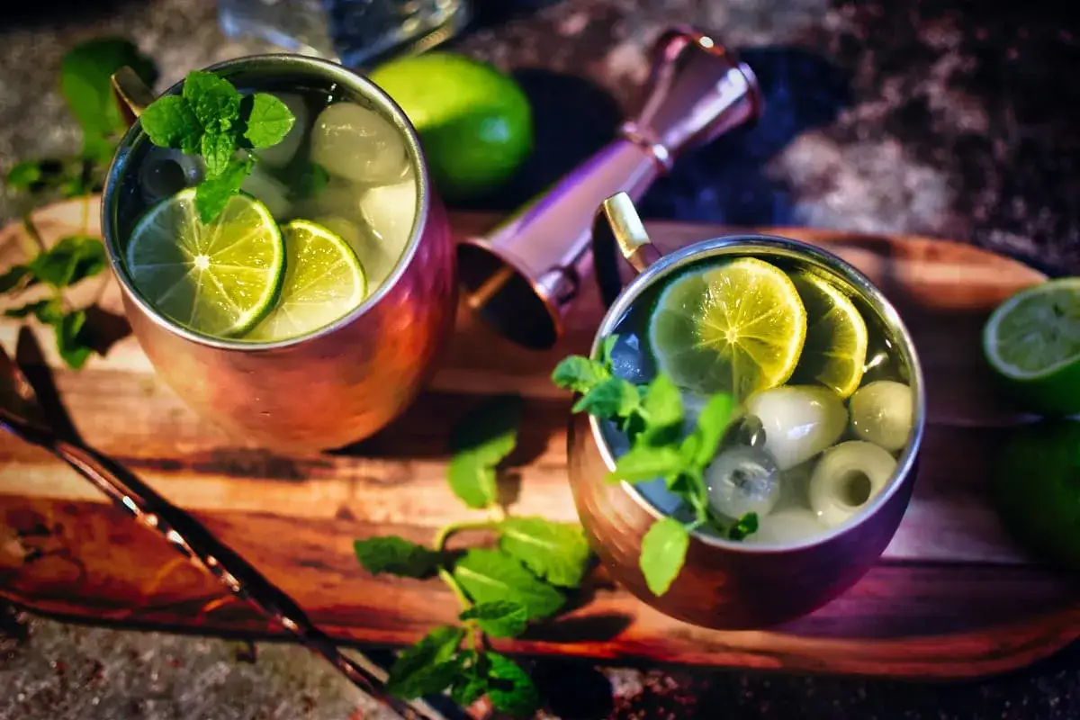 Zwei erfrischende Gin Mules in Kupferbechern, garniert mit Limettenscheiben und Minze, bereit zum Genießen.