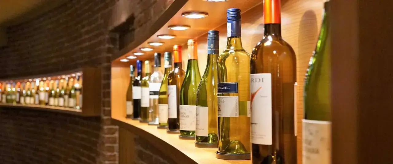 Regal mit vielen Flaschen Wein, die zum Spargel passen könnten. Helle und dunkle Flaschen stehen nebeneinander.