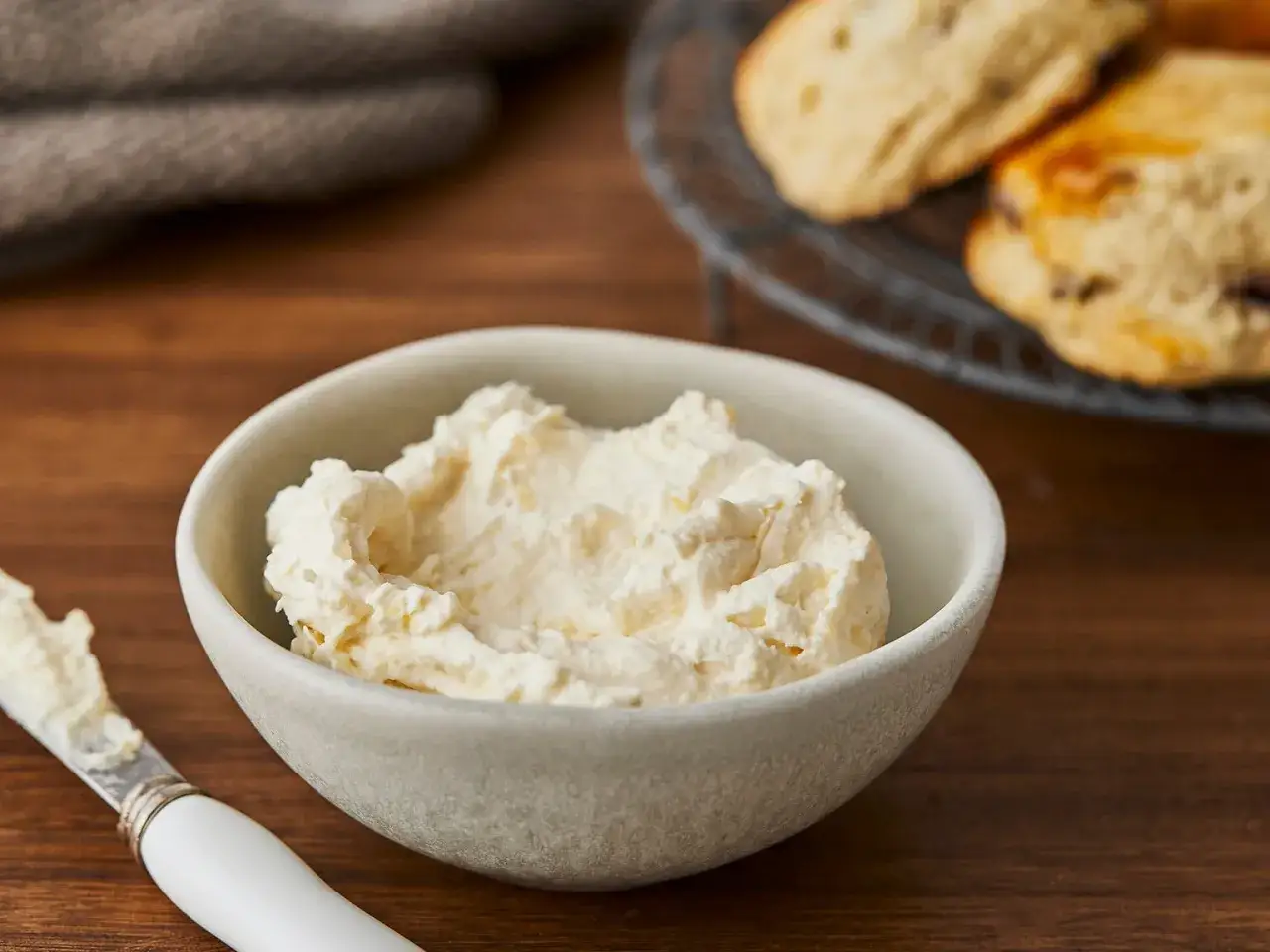 Cremiger Aufstrich in einer Schale, bereit für das perfekte Scones Rezept. Daneben ein Messer mit etwas Aufstrich.