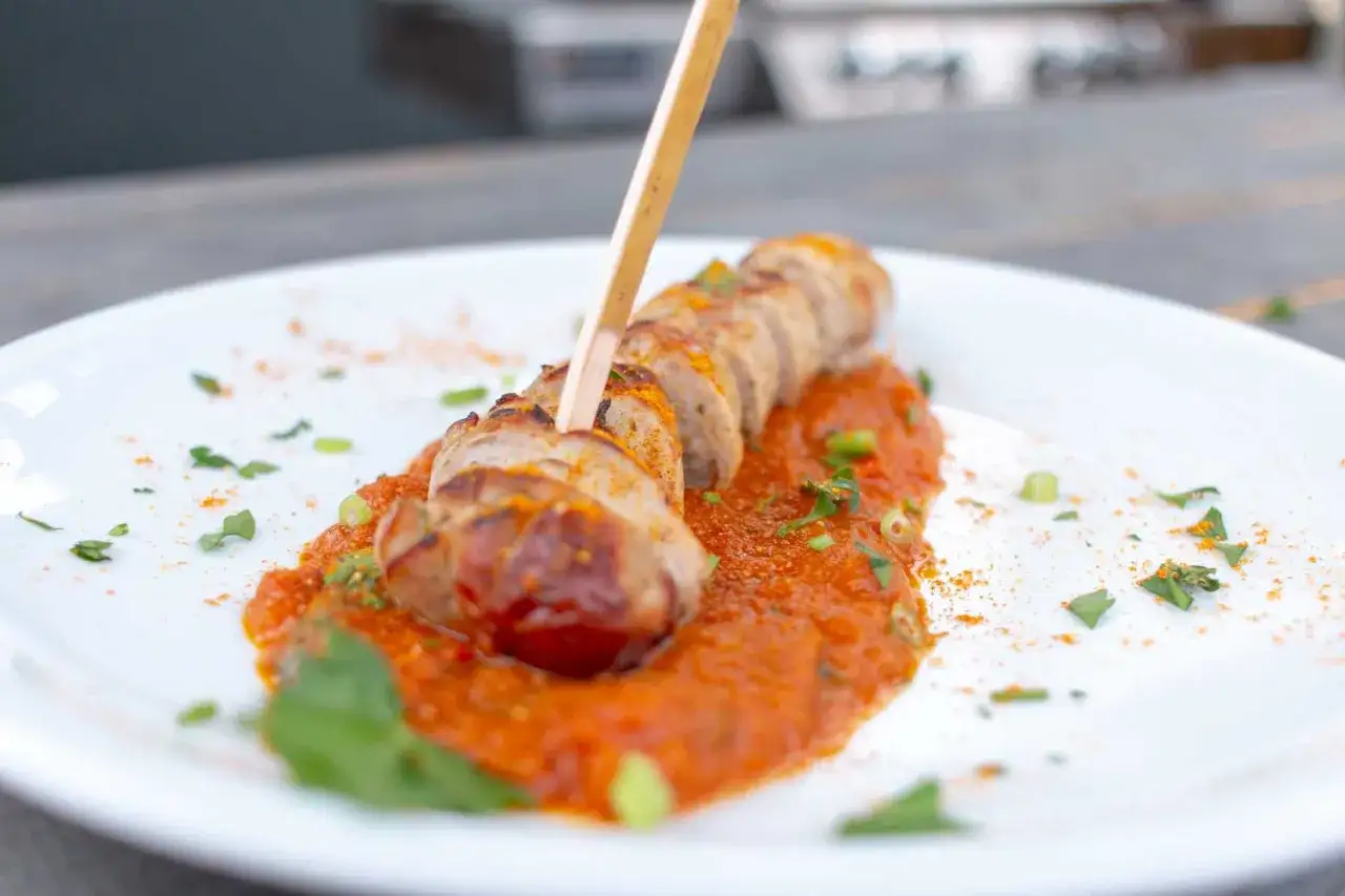 Eine köstliche Currywurst, aufgespießt und auf einer würzigen Tomatensoße mit Kräutern angerichtet. Perfekt für ein schnelles Currywurst Rezept.