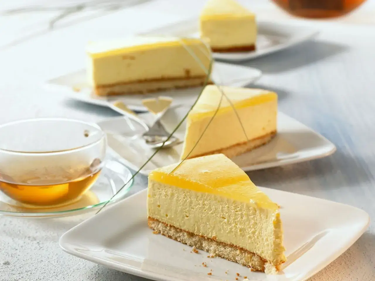 Ein Stück Maracuja Torte mit cremigem Käsekuchen und fruchtiger Maracuja-Gelee-Schicht. Dazu eine Tasse Tee.