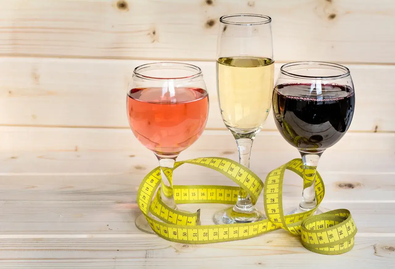 Drei Gläser Wein (rot, weiß, rosé) mit Maßband. Wein Kalorien im Blick behalten für eine bewusste Ernährung.