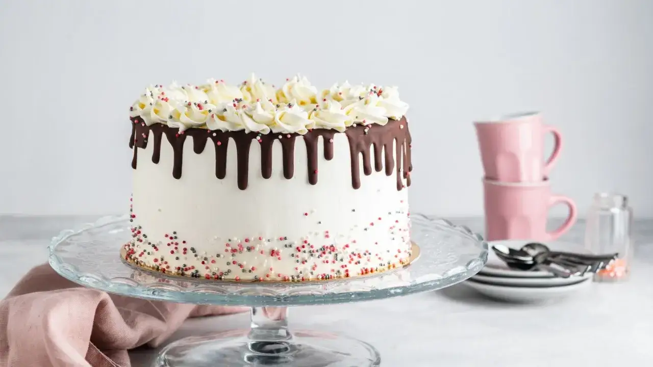 Eine wunderschöne weiße Torte mit Schokoladenglasur und Streuseln, die Lust auf beste Torten Rezepte macht.