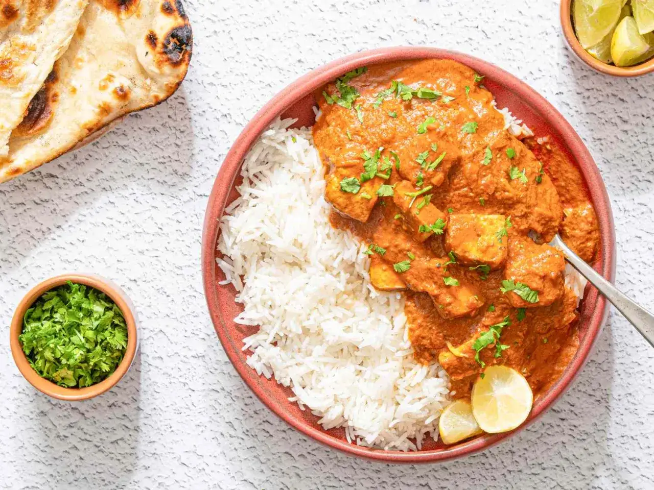Ein köstliches indisches Curry mit Reis, garniert mit Koriander und serviert mit Naan-Brot.