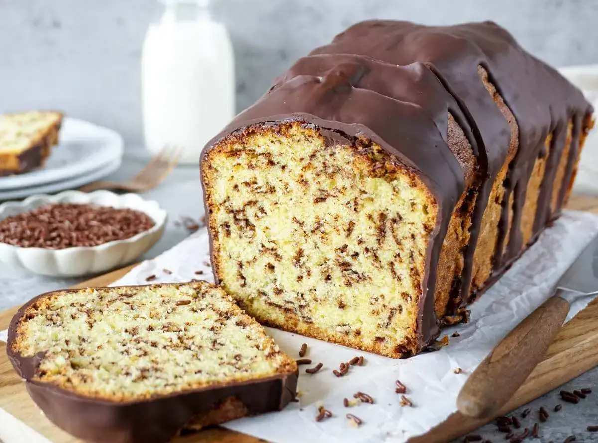 Schokoladenkuchen mit Streuseln, perfekt für Kuchen Rezepte. Ein Stück ist angeschnitten, daneben eine Schale mit Schokostreuseln.