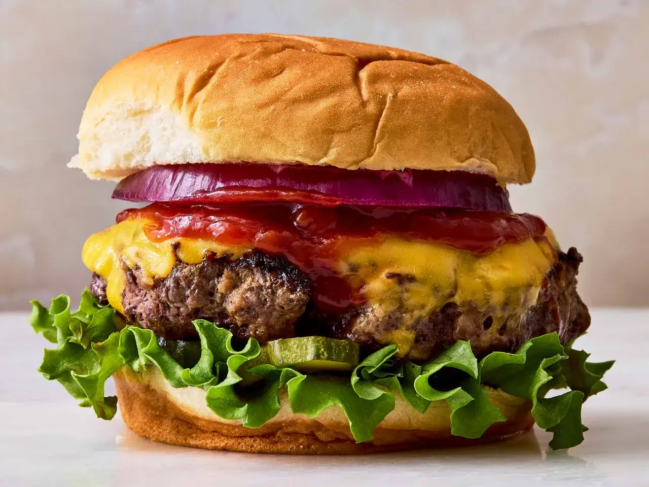 Saftiger Burger mit geschmolzenem Käse, knackigem Salat und roten Zwiebeln. Die Burger patties sind perfekt gegrillt.