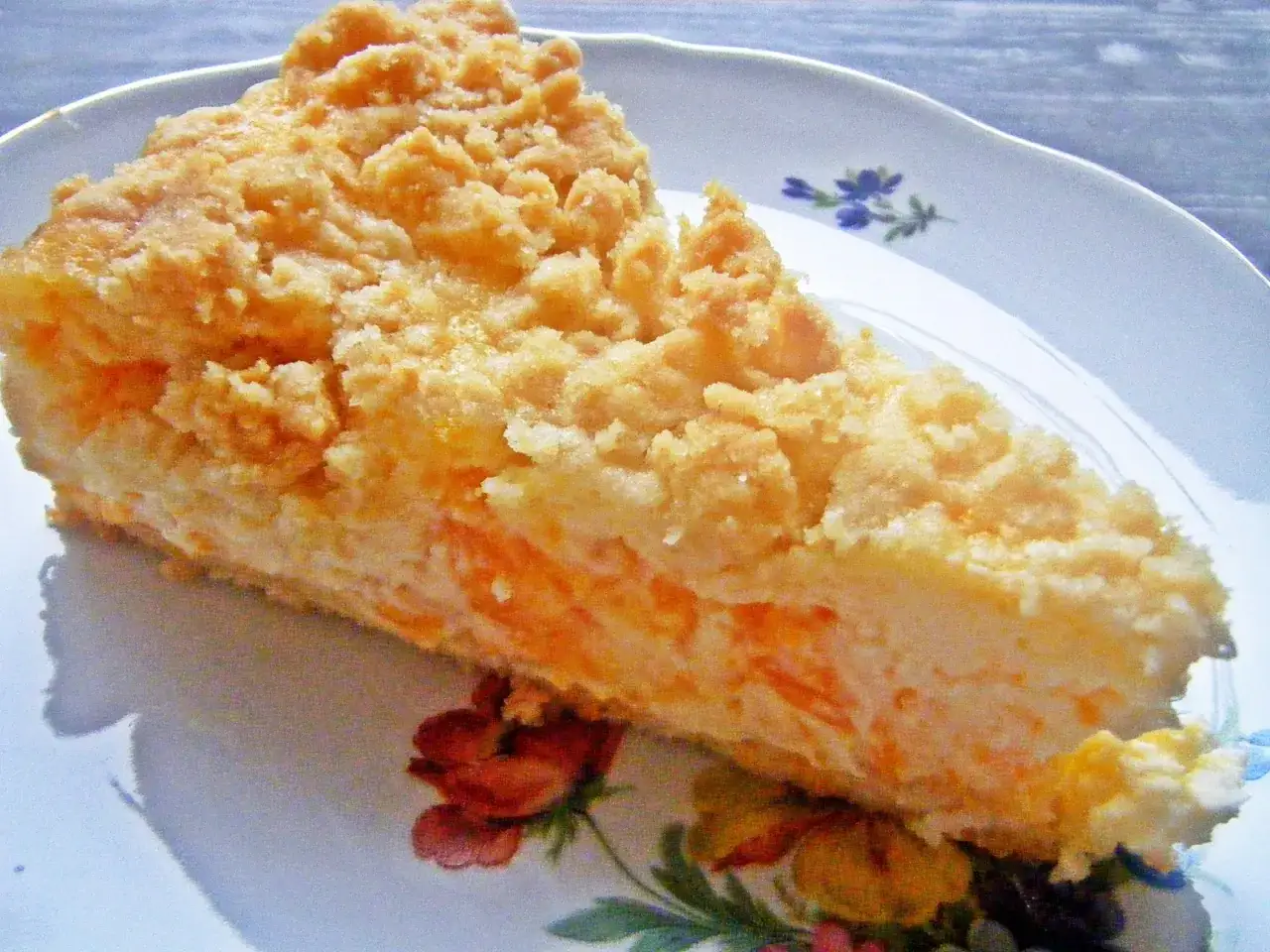 Ein Stück saftiger faule weiber kuchen mit Streuseln auf einem Teller mit Blumenmuster.