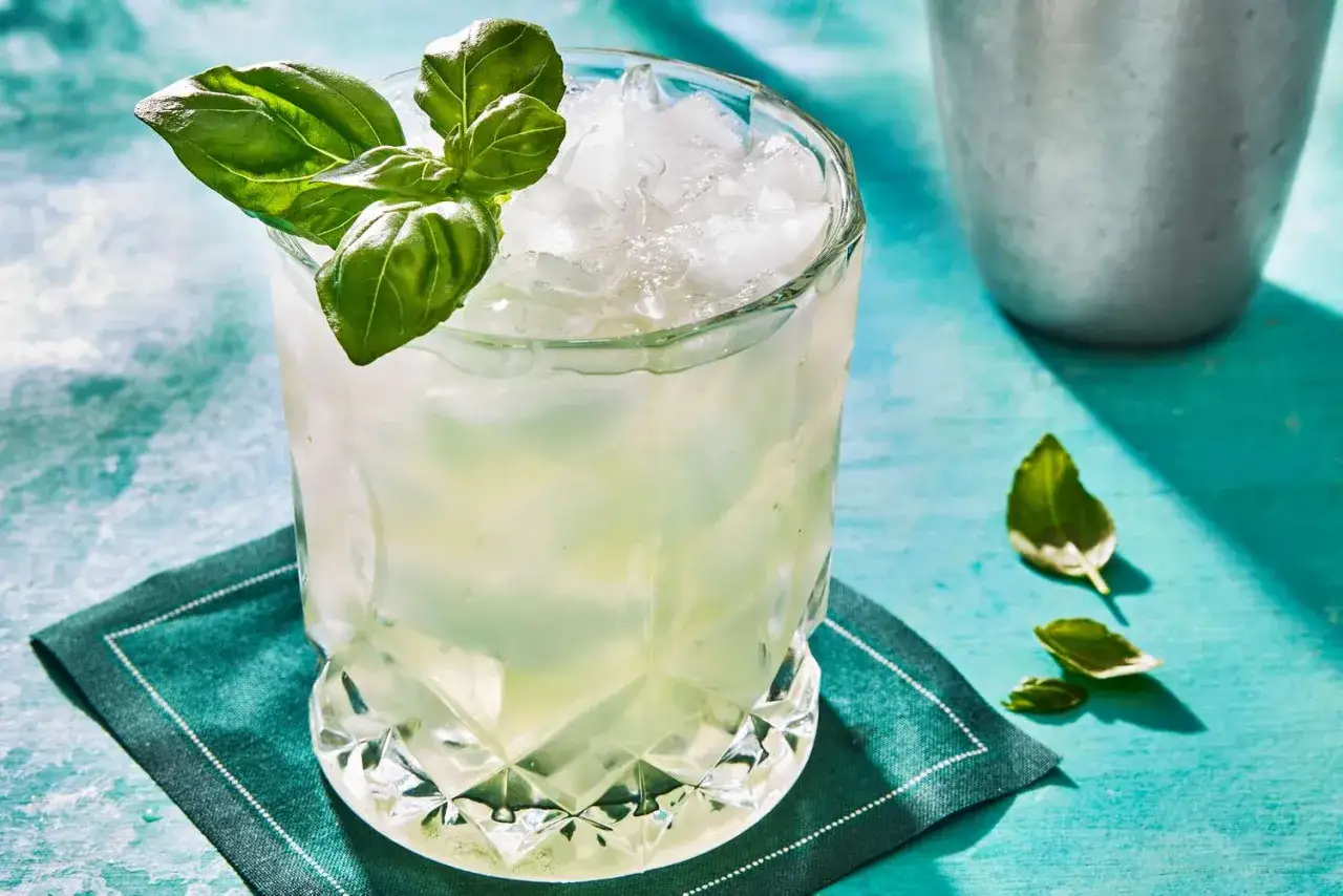 Erfrischender cocktail mit basilikum und gin, serviert mit Eis und garniert mit frischen Basilikumblättern.