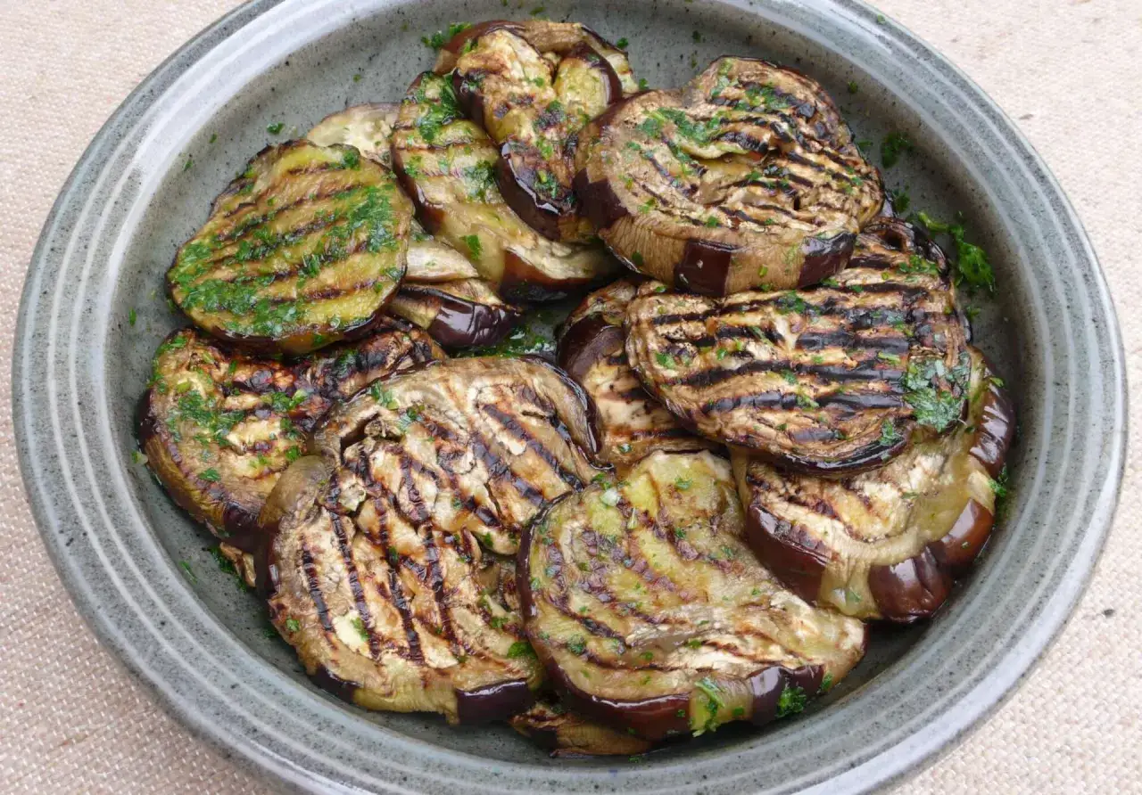 Gegrillte Auberginenscheiben mit Kräutern in einer Schale. Perfekt für den Sommer, das Aubergine grillen ist eine köstliche Zubereitung.