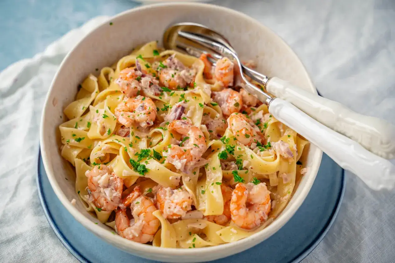 Bandnudeln mit Garnelen in cremiger Sauce, bestreut mit Petersilie. Perfekt zu einem Glas Weißwein.