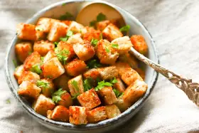 Goldbraune, knusprige Croutons, frisch zubereitet, garniert mit Petersilie in einer Schüssel. Perfekt zum **Croutons selber machen** für Salate oder Suppen.