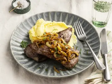 Leber braten mit karamellisierten Zwiebeln und Kartoffelpüree auf einem grauen Teller. Ein Klassiker, der immer schmeckt.