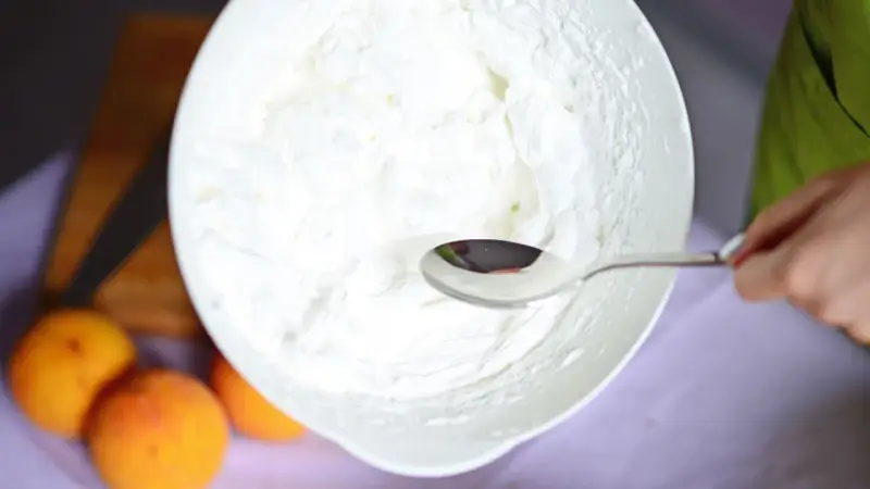 Eine Schüssel mit frisch geschlagener Sahne, bereit für ein Dessert. Ein Löffel ruht in der luftigen Masse.
